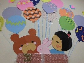 写真1：気球にクマとうさぎと女の子が乗っている