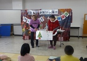 大型絵本『クリスマスのかくれんぼ』の読み聞かせを親子で聞いている画像