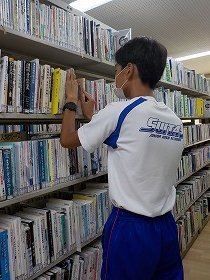 本棚で本の整理をしている画像