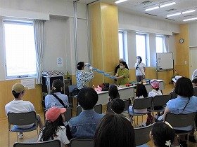 写真1：おたのしみ塾の方がバルーンアートを作っている様子を見る参加者