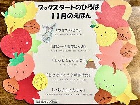 「ブックスタートのひろば」11月に読む絵本を紹介したポスターの画像。リンゴ、梨、栗と、赤や黄色の紅葉、絵本のキャラクターの飾り付けがされています。