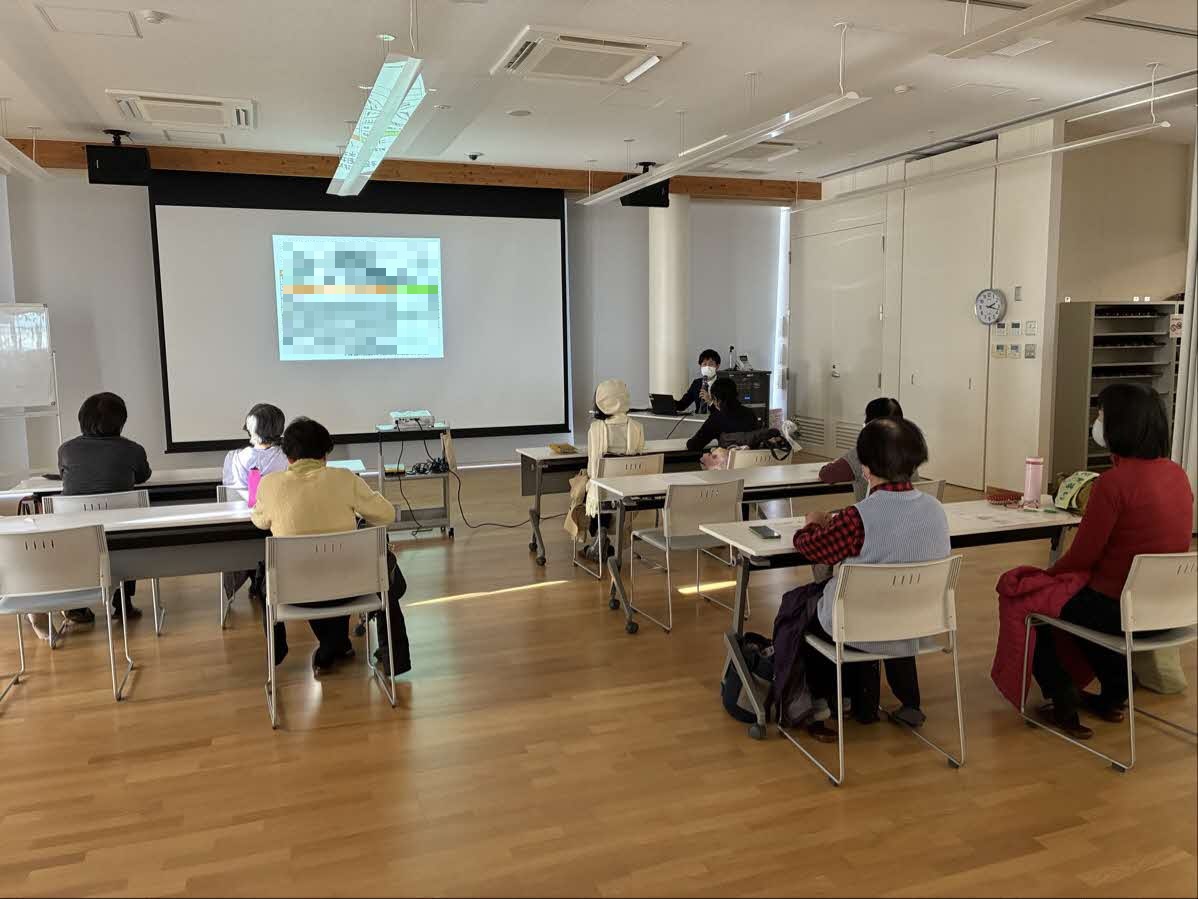 写真1：健康医療情報講座「がんについて」でスクリーンを見ながら講師のお話を聴いている参加者の様子。