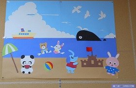 海でクマとウサギが泳ぎ砂浜でパンダがスイカを食べている様子を画用紙と折り紙で表現した装飾の画像