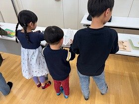 写真3 子供たちが点字絵本やさわる絵本の展示を見ている様子の画像