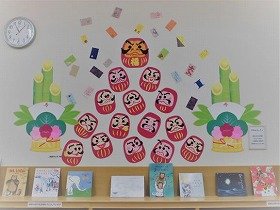 写真 門松に挟まれてだるまがピラミッド状に積みあがっている壁面装飾の画像