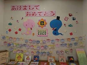 写真3 絵馬がいっぱい飾られ蛇もにっこりしている壁面装飾の画像