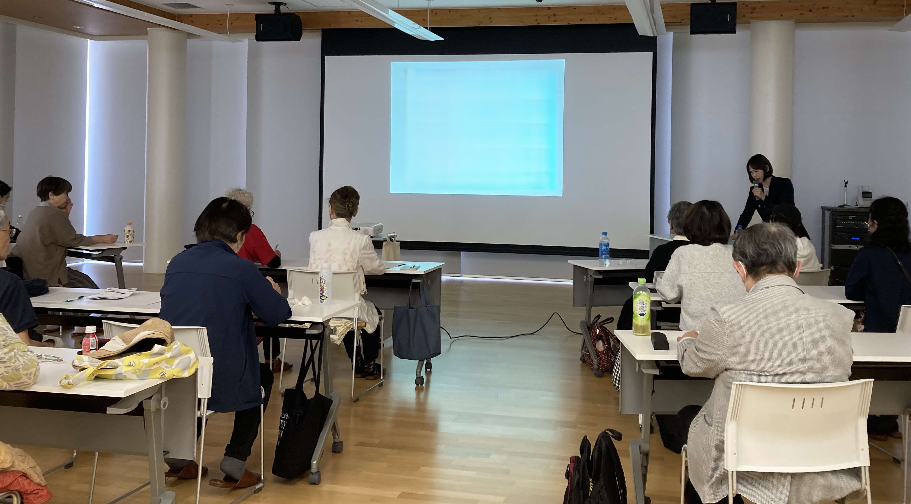 写真健康医療情報講座「身近な健康パートナー、薬剤師との付き合い方」で講師のお話に耳を傾けながら前方のスクリーンを見ている参加者の様子。