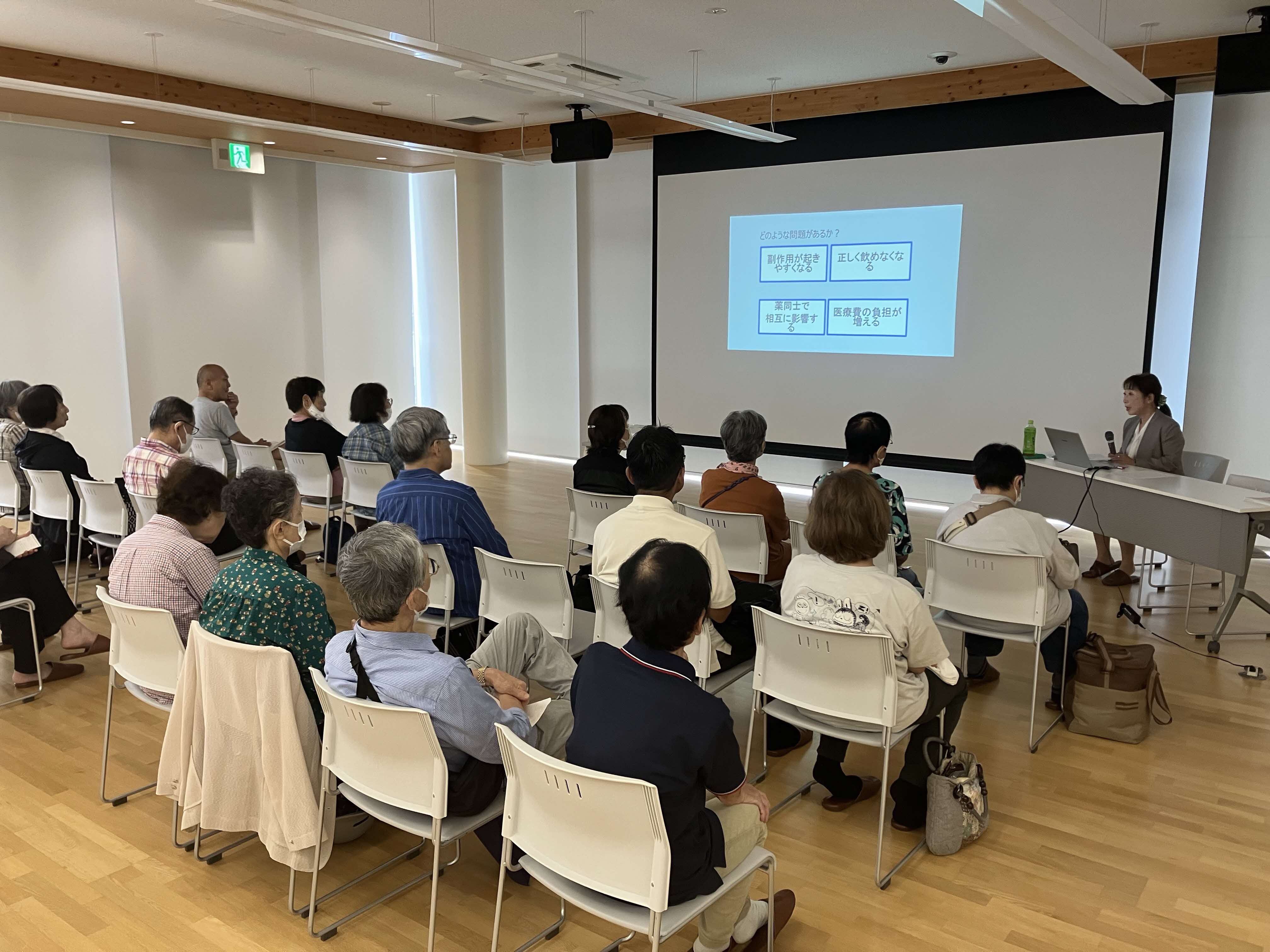 健康医療情報講座「ポリファーマシーについて－お薬が多いことで起こる困りごと－」でスクリーンを見ている参加者の様子。