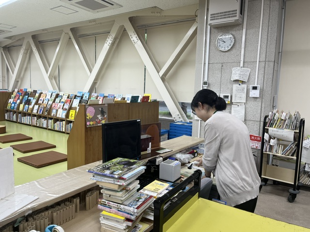写真返却本の確認作業中。機械でバーコードを読み取っています。
