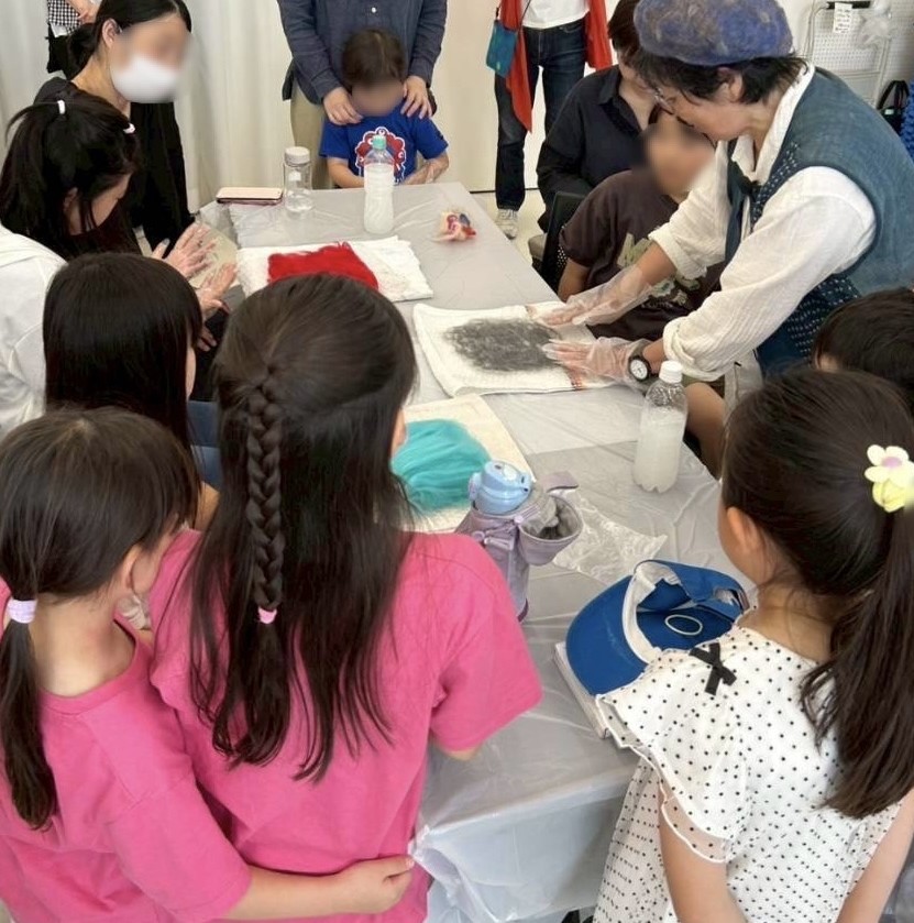 コースターの作り方を教わっている様子。