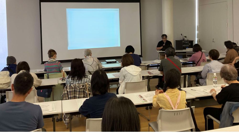 健康医療情報講座「自分でできる「こころのセルフケア」」で配布資料を見ながら講師の説明を聞いている参加者の様子