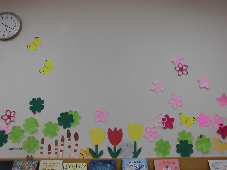 画像：花やクローバーの上を蝶々が飛んでいる壁面飾り