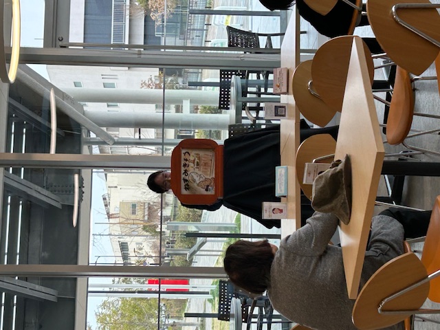 写真：健康カフェで、紙芝居『ねずみきょう』を読み聞かせしているプログラム研修生。