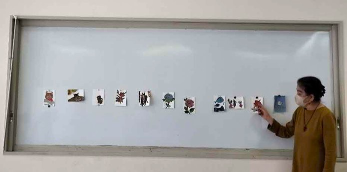 画像3　ホワイトボードに貼られた参加者の作品を、講師が紹介している様子。