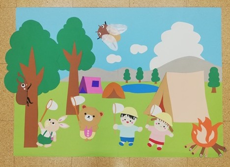 広い野原にテントがあり、子供たちが虫取り網を持ってカブトムシやセミを捕まえようとしている。