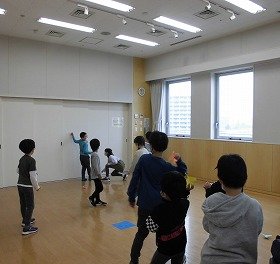 子どもたちが紙ひこうきを飛ばして遊んでいる様子