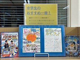 写真　YAコーナーに展示している『部活で差がつく！バスケットボール弱点克服マニュアル』と『約束のネバーランド　[1]　ノーマンからの手紙』と、職業体験生が一つずつ作成したそれぞれのPOP