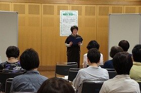 吹田おはなしの会の女性の方1人が、朗読をしている写真。