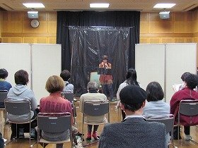 吹田おはなしの会の女性の方一人が、ハーモニカを演奏している様子。