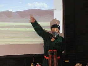 島村一平先生がモンゴルの大草原の写真を指をさして話している様子。