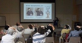 肩こり予防ストレッチの説明をする栗村先生とストレッチをする参加者のみなさん。