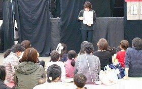 写真2：人形劇サークル花かごのメンバーの一人がなぞなぞをしている写真。