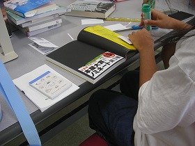 写真本の紹介文が書かれた帯を貼っている様子