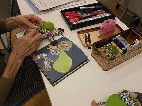 受講生が絵本をみながら人形を縫う作業をしている様子