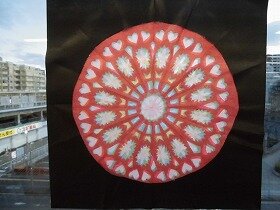 ピンクや水色の紙を重ねた円形のステンドグラスのような切り紙装飾の拡大画像
