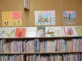 山田駅前図書館絵本コーナーの壁飾り。満開のサクラの下でお花見をしている動物たちの絵や赤、青、緑と色