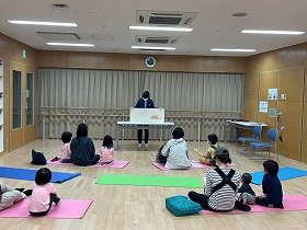 大型絵本『おしくらまんじゅう』を親子で見ている様子。