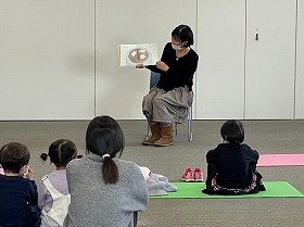 子供たちに向かって、絵本『おもち』を読み聞かせている様子。