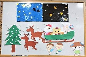 写真　星空。雪が降っている。雪が詰まったもみの木。サンタクロースとプレゼントの袋と動物たちがのったソリ。ソリを引く2匹のトナカイ。子どもたち。12月の壁面装飾です。