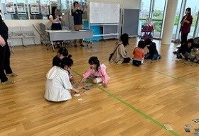 写真1　留学生がカルタの読み札を読み、子どもたちがそれを聞いて絵札を探している様子