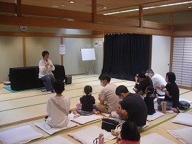 お話「若がえりの水」お話をきいたあと、演者と一緒に参加者も手遊びをしているところ。