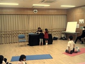 演者が組木のゾウやカバを子供たちといっしょに四角い箱に片付けています。