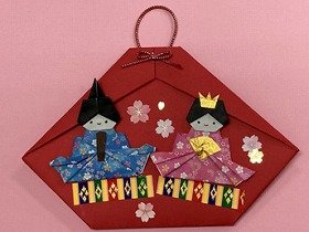 画像　貝がらの形をした赤い毛氈（もうせん）の上に座る、おだいりさまとおひなさまの折り紙作品。