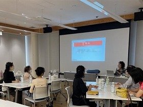 写真　机を囲みながらスクリーンを見ている参加者の様子。