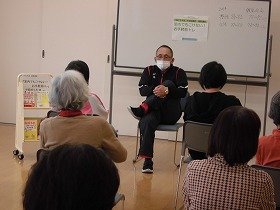 講師の動きを真似て、椅子に座ってできるストレッチをする参加者のみなさん。