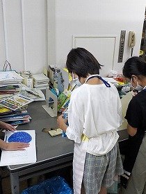 1日図書館員が、新しく入ってきた絵本に開きぐせをつけている様子。