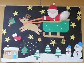 写真1：トナカイが引くそりにのったサンタクロースがプレゼントを届けに行く様子を、画用紙と折り紙で表現しています。