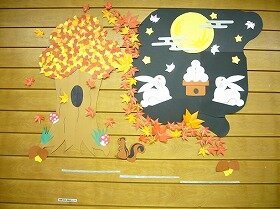 画用紙や折り紙で作ったお月見をしているうさぎ、色づいた紅葉と木と側にいるリスの装飾。