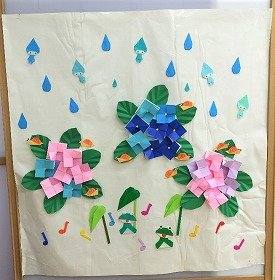 写真　大粒の雨に、雨の妖精が何人か混じっている。満開のアジサイの葉の上にカタツムリたち。カエルたちは歌を歌っている。