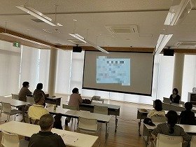 写真1：健康医療情報講座「薬の悩み・疑問、解決します！」で前方のスクリーンを見ながら講師のお話を聞いている参加者の様子。