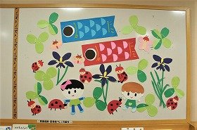 写真　こいのぼり。2人の子ども。菖蒲の花。クローバー。てんとう虫。ちょうちょ。5月の壁面装飾です。