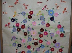 折紙による壁面装飾。色とりどりの草花の上でたくさんの赤トンボが飛んでいる。
