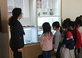 博物館の展示コーナーで説明を聞く子供たち。