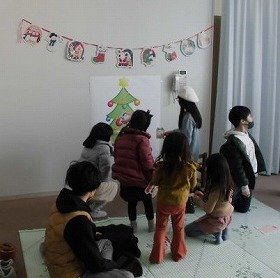 子どもたちがツリーの絵に飾りつけをしている様子。