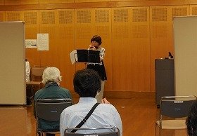 吹田おはなしの会の女性の方１人が、クロマチックハーモニカを演奏している写真。