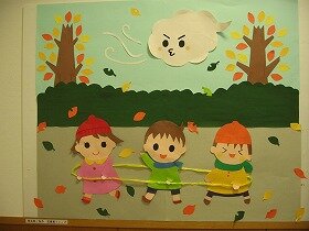 落ち葉が舞い散るなか、3人の子どもが電車ごっこをしている壁面飾り